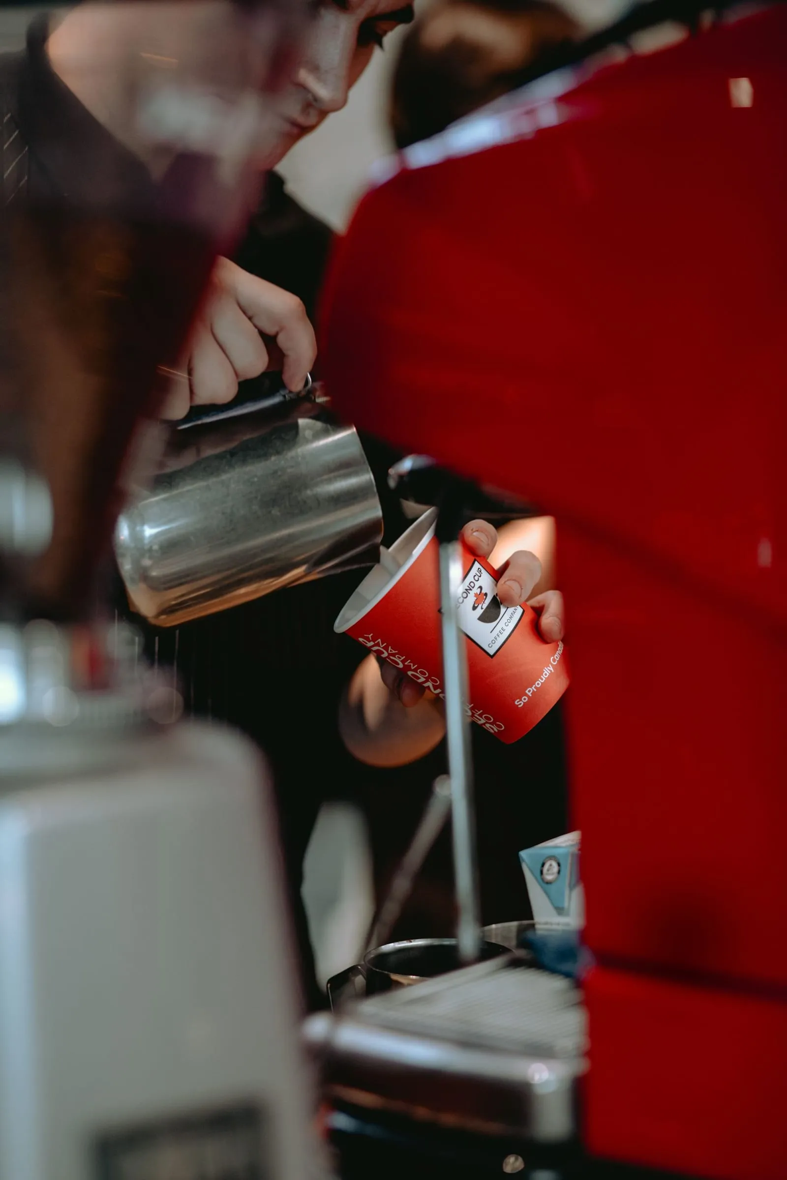 Barista che versa il latte in una tazza rossa